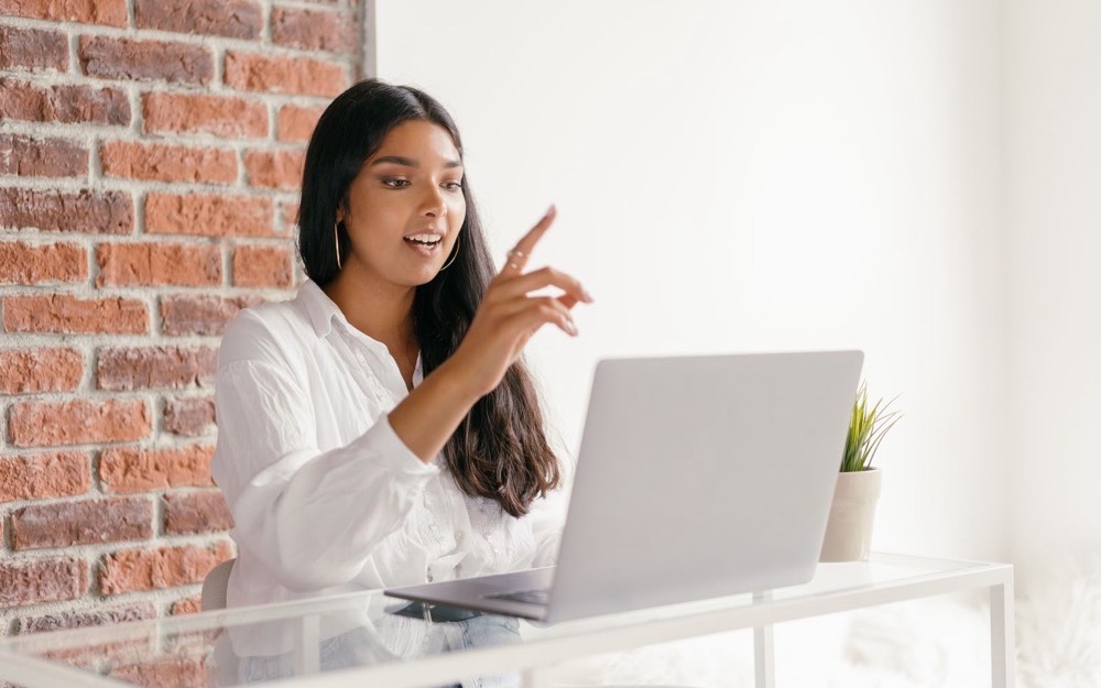 Una mujer conversa en una videollamada desde su notebook y gesticula con atención